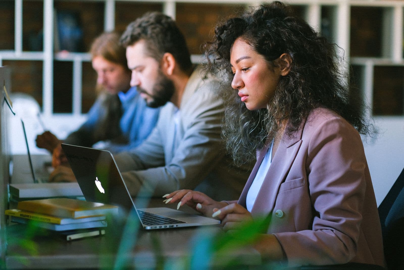 Drei Mitarbeitende arbeiten konzentriert an Laptops in einem Büro